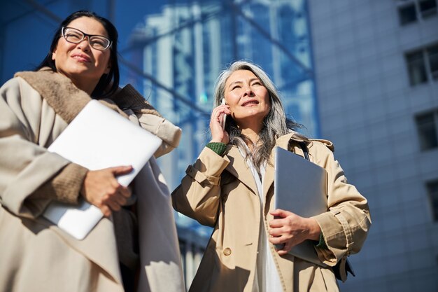 Donne eleganti con laptop in piedi per strada