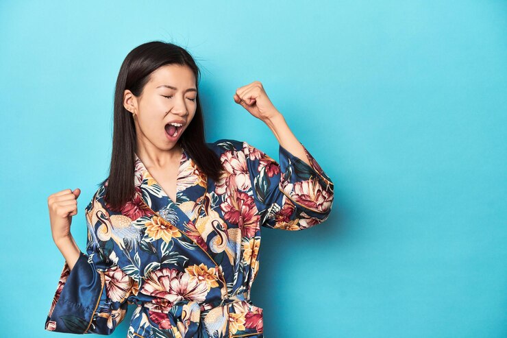 Photo キモノを着たエレガントな若いアジア人女性が 勝利のコンセプトの後で拳を上げて撮影しました