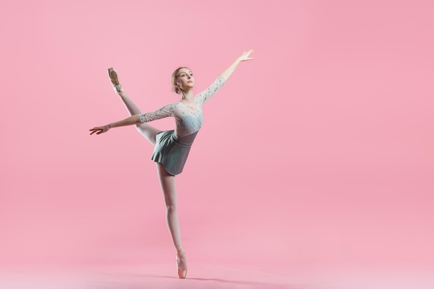 Photo elegant young ballerina in pointe shoes dancing on a delicate pink background