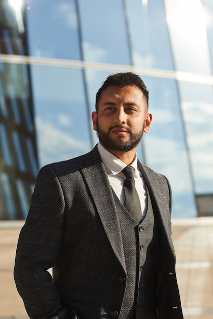 Elegant young bearded businessman in black suit standing in the city outdoors