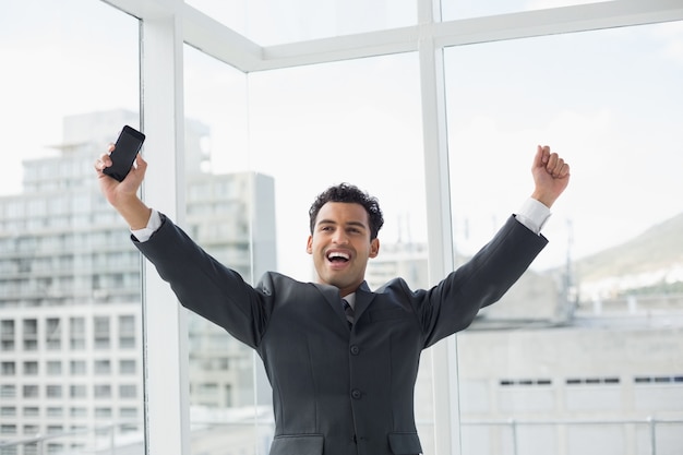 Elegant young businessman cheering in office