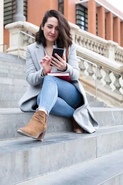 Elegante giovane donna caucasica tramite telefono cellulare