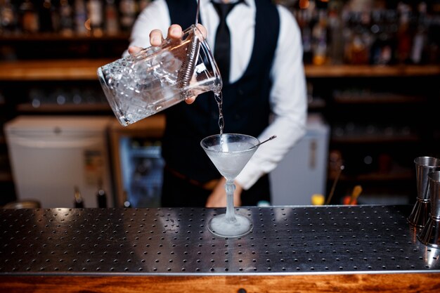 Elegant young male barman prepares a delicious cocktail