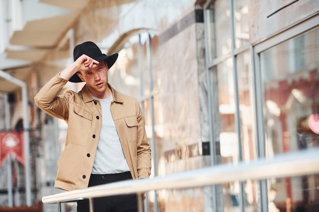 Elegant young man in black hat and formal classy clothes outdoors in the city