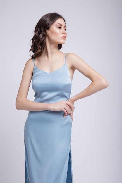 элегантная молодая женщина в красивом синем платье, позирует на белом фоне. Стройная фигура, студийный снимок