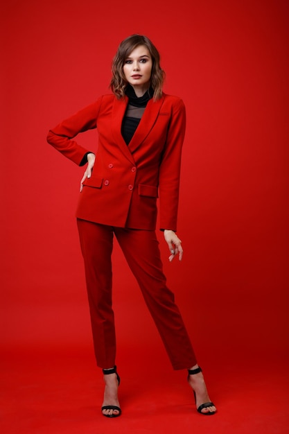 Elegant young woman in red suit jacket pants trousers black blouse on background Monochrome