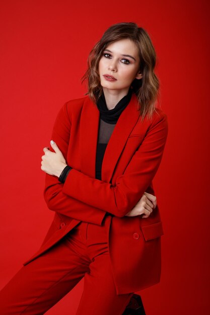 Elegant young woman in red suit jacket pants trousers black blouse on background Monochrome