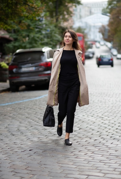 Elegant young  woman in trendy outfit crossing city street. Full length shot