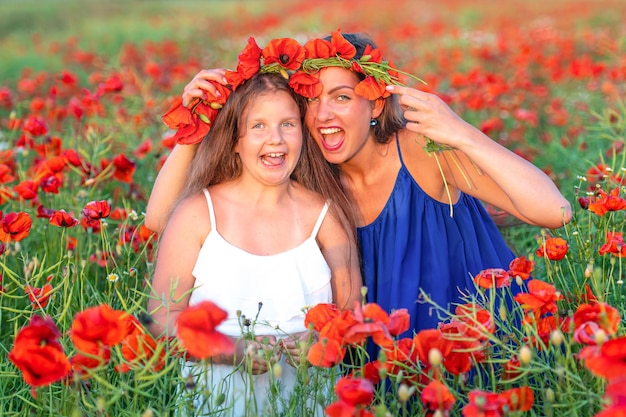 Elegant young woman with child girl in poppy field happy family having fun in nature summer time