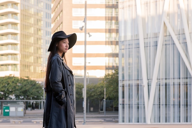 Elegante Aziatische vrouw die in hoed de stad in loopt