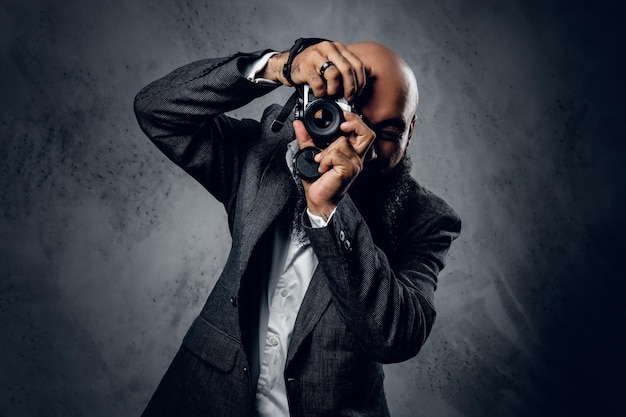 Elegante bebaarde professionele fotograaf in een pak fotograferen met een compacte DSLR-camera.