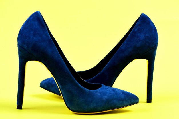 Elegante blauwe schoenen geïsoleerd op gele achtergrond. Paar blauwe suède schoenen met hoge hakken. Mode en beauty concept. Vrouwelijke formele schoenen, zijaanzicht.