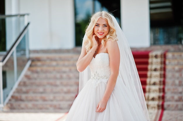 Elegante blonde blauwe ogen mode bruid in grote trouwzaal op rode loper