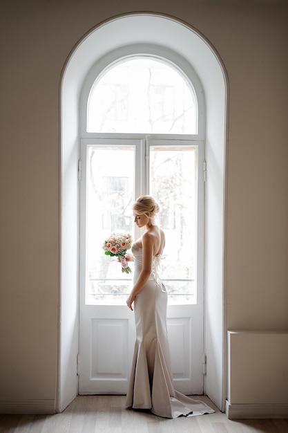 Elegante blonde bruid in een mooie witte jurk met een bruiloft boeket