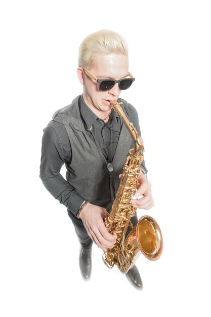 Elegante blonde man gekleed in het zwart spelen van de saxofoon geïsoleerd