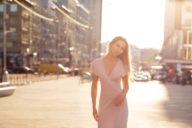 Elegante blonde model poseren op straat in een stralen van de zon. Levensstijl mode concept. Ruimte voor tekst