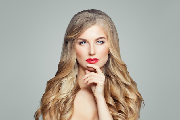 Elegante blonde vrouw met lang golvend haar Denken fashion model portrait