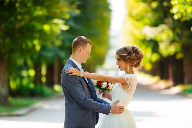 Elegante bruid en bruidegom poseren samen buitenshuis op een trouwdag