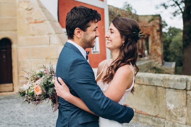 Elegante bruid en bruidegom poseren samen buitenshuis