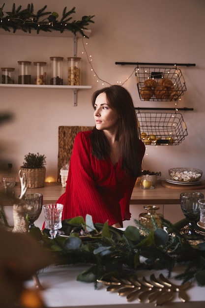 Elegante brunette vrouw in rode jurk in het interieur van de keuken ingericht voor Nieuwjaar.