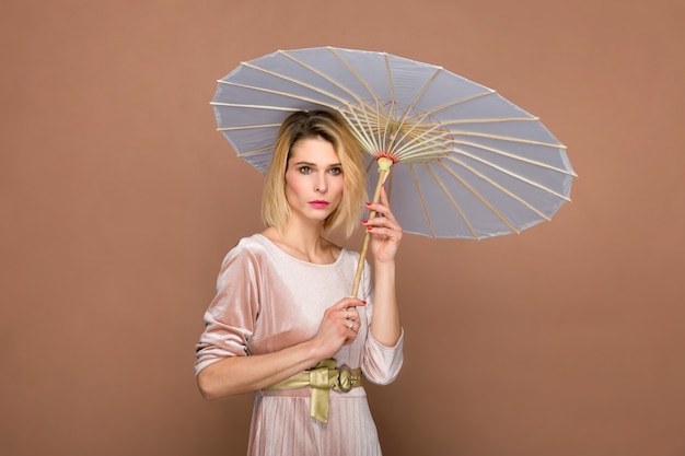 Elegante dame in chenille pak met parasol of oosterse parasol poseren op bruine muur