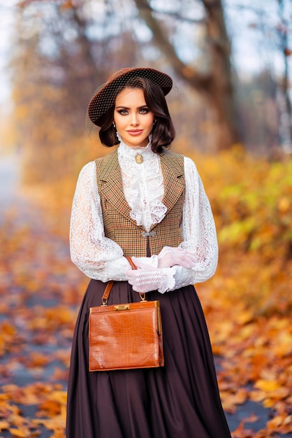 Elegante dame in vintage kanten jurk die op de herfstachtergrond staat