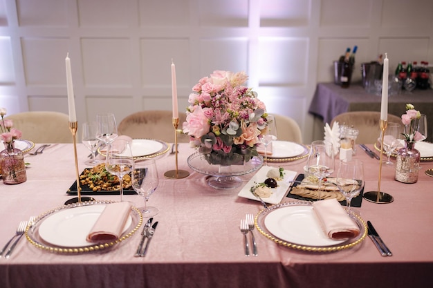 Elegante decoratie van de tafel in restaurant roze tafelkleed stijlvol bestek en prachtige bloemen