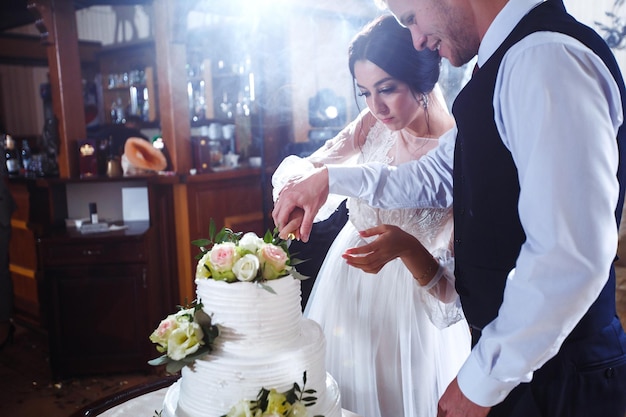 Elegante en stijlvolle bruidstaart met bloemen Jonggehuwden staan in de buurt van een grote bruidstaart
