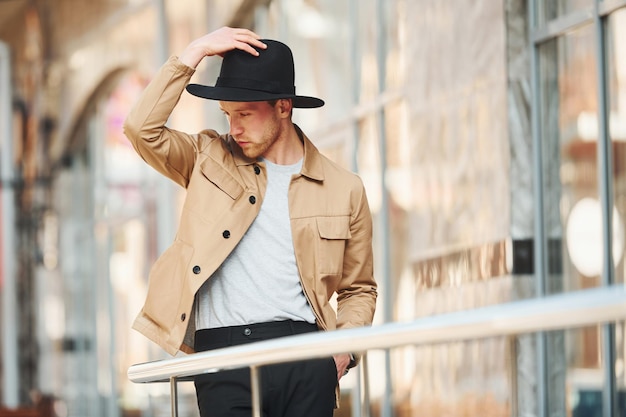 Elegante jonge man in zwarte hoed en formele stijlvolle kleding buiten in de stad