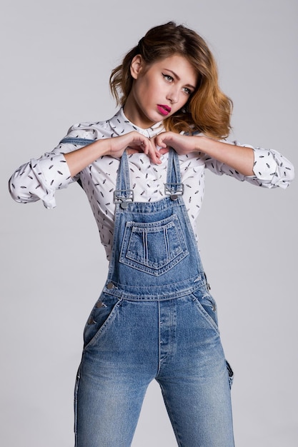 elegante jonge vrouw in jeans denim jumpsuit, shirt poseren op witte achtergrond