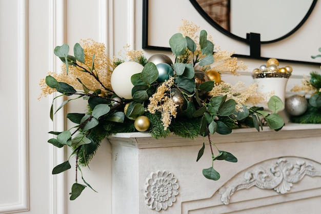 Elegante kerstkrans met gouden en zilveren kerstballen op een open haard Licht interieur in wittinten