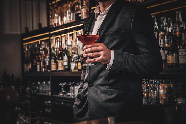 Elegante knappe man in klassiek pak drinkt alcohol aan de leuke bar.