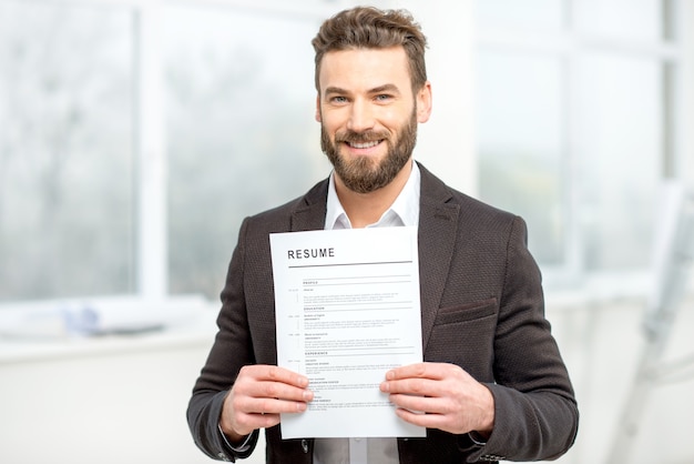 Elegante man in het pak met cv voor het inhuren van een baan in het lichte interieur