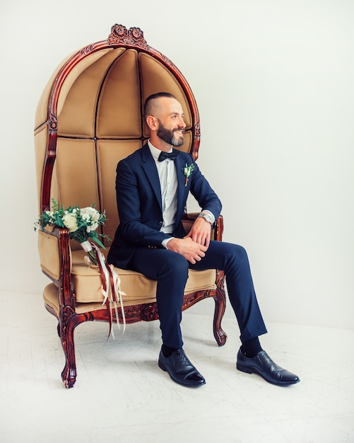 Elegante man zittend in een stoel en ergens op zoek naar de zijkant.