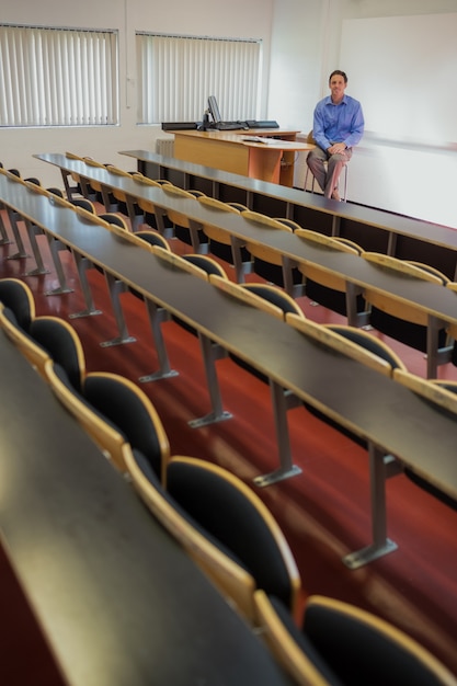 Elegante mannelijke leraar zitten in de collegezaal