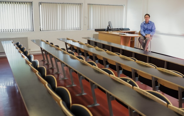 Elegante mannelijke leraar zitten in de collegezaal