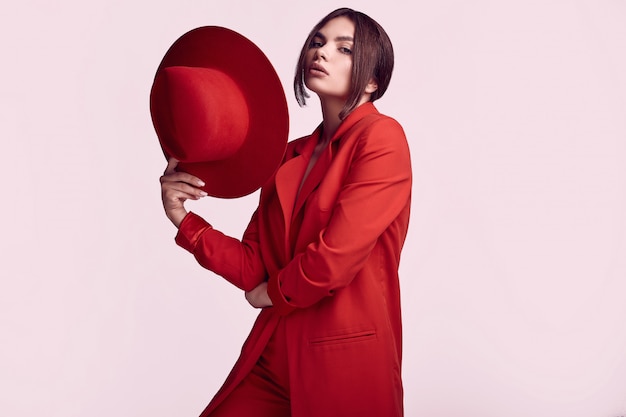 Elegante mooie vrouw in een rood modieus pak en brede hoed