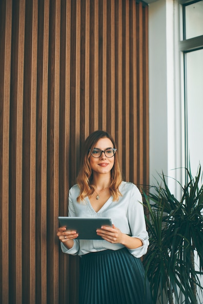 Elegante onderneemster die zich in bureau met digitale tablet bevindt