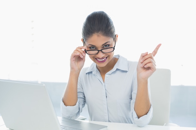 Elegante onderneemster met laptop zitting bij bureau