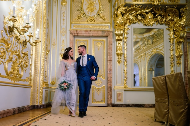 Elegante prachtige bruid en stijlvolle bruidegom in geweldige oude rijke kamer. Luxe huwelijksconcept