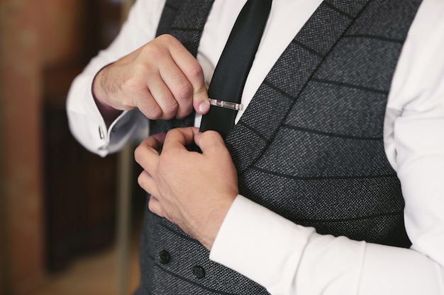 Foto elegante prachtige bruidegom klaar in de ochtend in de hotelkamer, met clip op zijn das