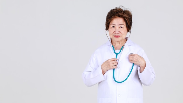 Elegante senior vrouwelijke arts op doktersjurk die vol vertrouwen staat als ziekenhuisgezondheidsdeskundige voor ziektebehandeling in de kliniek.