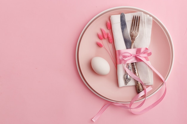 Elegante stijlvolle tafel instelling. Mes en vork op een servet op een bord op een roze oppervlak.