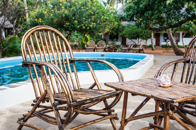 Elegante stoelen van hout bij een zwembad in een Keniaanse tuin