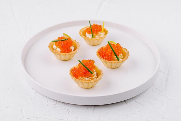 Foto elegante tartlets met zalmkaviaar op een wit bord