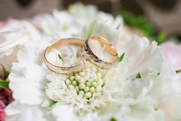 Foto elegante trouwverlovingsringen op witte bloemen
