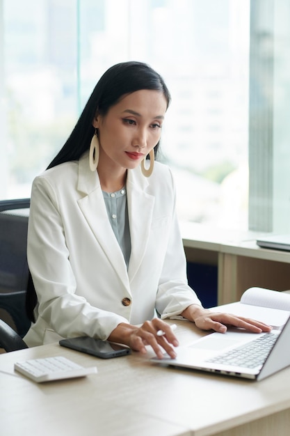 Elegante vietnamese ondernemer die op laptop werkt