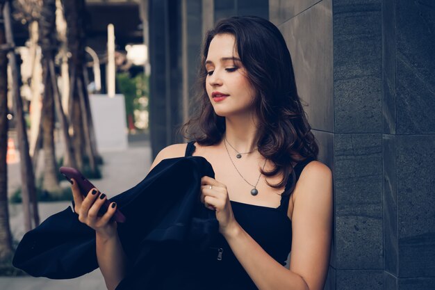 Elegante vrouw buiten kantoor en met behulp van mobiele telefoon.