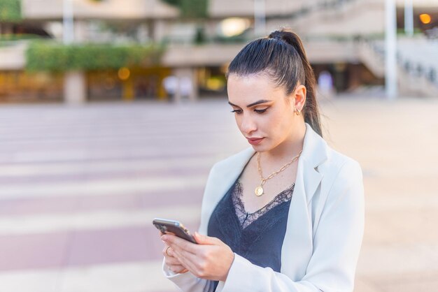 Elegante vrouw die op haar mobiele telefoon typt. Horizontale onscherpe achtergrond