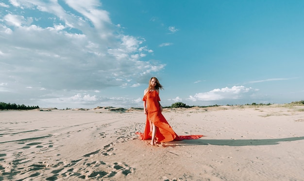 elegante vrouw die zich voordeed op het strand met rode jurk